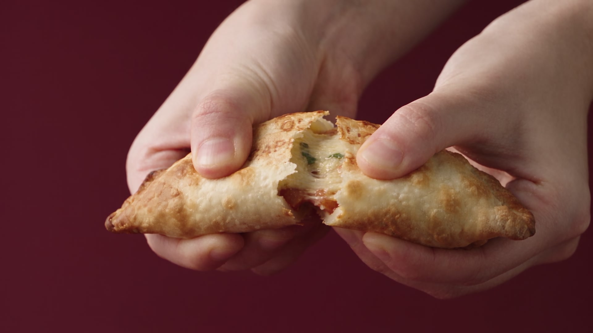 Une empanada Nazca ouverte à la main, fromage fondant et pâte dorée
